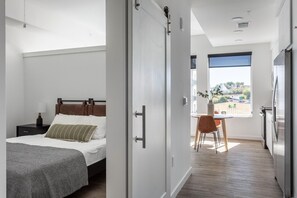 Une chambre d’hôtel moderne, équipée d’un lit, d’une table de chevet et offrant une vue sur l’extérieur.