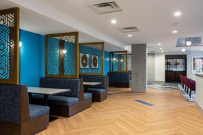 A modern restaurant with blue booths and a herringbone wood floor.