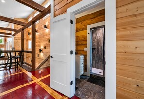 Un interior de madera con piso rojo y amarillo, una puerta blanca y una escalera que conduce a una habitación con vistas.