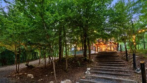 A wooden staircase leading to a building surrounded by trees. - Creek Bluff Retreat for Large Families and Groups (Broken Bow)