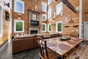 A spacious living room with a large sectional sofa, a fireplace, and a dining area with a wooden table and chairs.