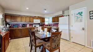 A kitchen with wooden cabinets, a dining table with chairs, a microwave, and a refrigerator. - Families, Fishermen & Hunters. Pleasant 3-bedroom house and dock ready for you! (Eufaula)