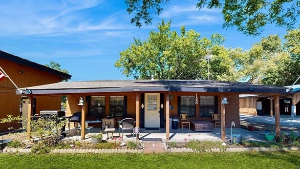 A single-story building with a covered porch, outdoor seating, and a small garden area. - Families, Fishermen & Hunters. Pleasant 3-bedroom house and dock ready for you! (Eufaula)