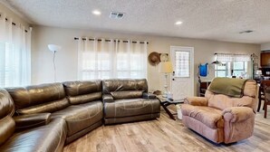 A living room with a sectional sofa and a single armchair, a lamp, and a window with curtains. - Families, Fishermen & Hunters. Pleasant 3-bedroom house and dock ready for you! (Eufaula)