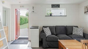 A modern living room with a grey sofa, a wooden coffee table, and a kitchen area with a window. - Östra Stranden by Interhome (Halmstad)
