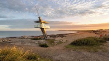 A coastal landscape with a unique, modern lookout tower structure.