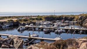 Un puerto deportivo con varias embarcaciones amarradas, rodeado de terreno rocoso y una vista despejada del mar.