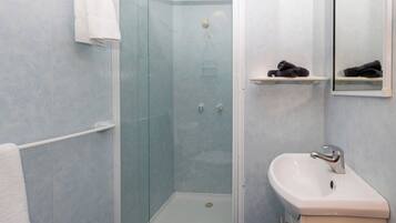 A bathroom with a glass-enclosed shower, a white sink, and a towel rack.