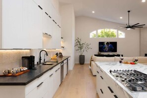 Een moderne keuken met een centraal eiland, een zithoek met een bank, een televisie en een plafondventilator.