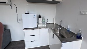 Et lille tekøkken med indbygget køleskab, kaffemaskine og vanddispenser.