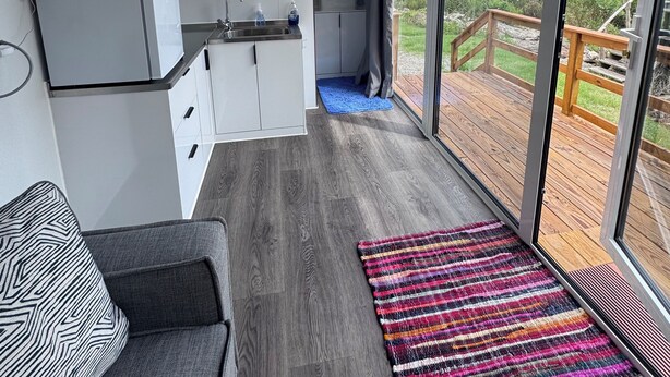 Et moderne køkken med hvide skabe, en indbygget ovn og et stort vindue med udsigt over en terrasse.