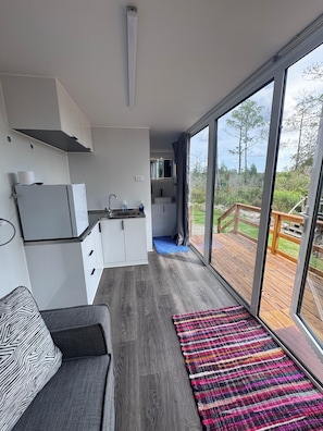A modern kitchen with white cabinets, a built-in oven, and a large window overlooking a deck.