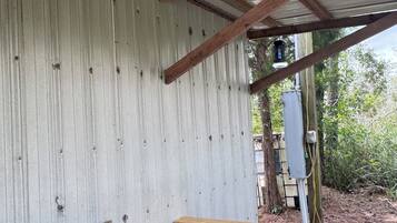 Eine rustikale Außenküche mit Spüle aus Metall, Holztisch und Deckenventilator.
