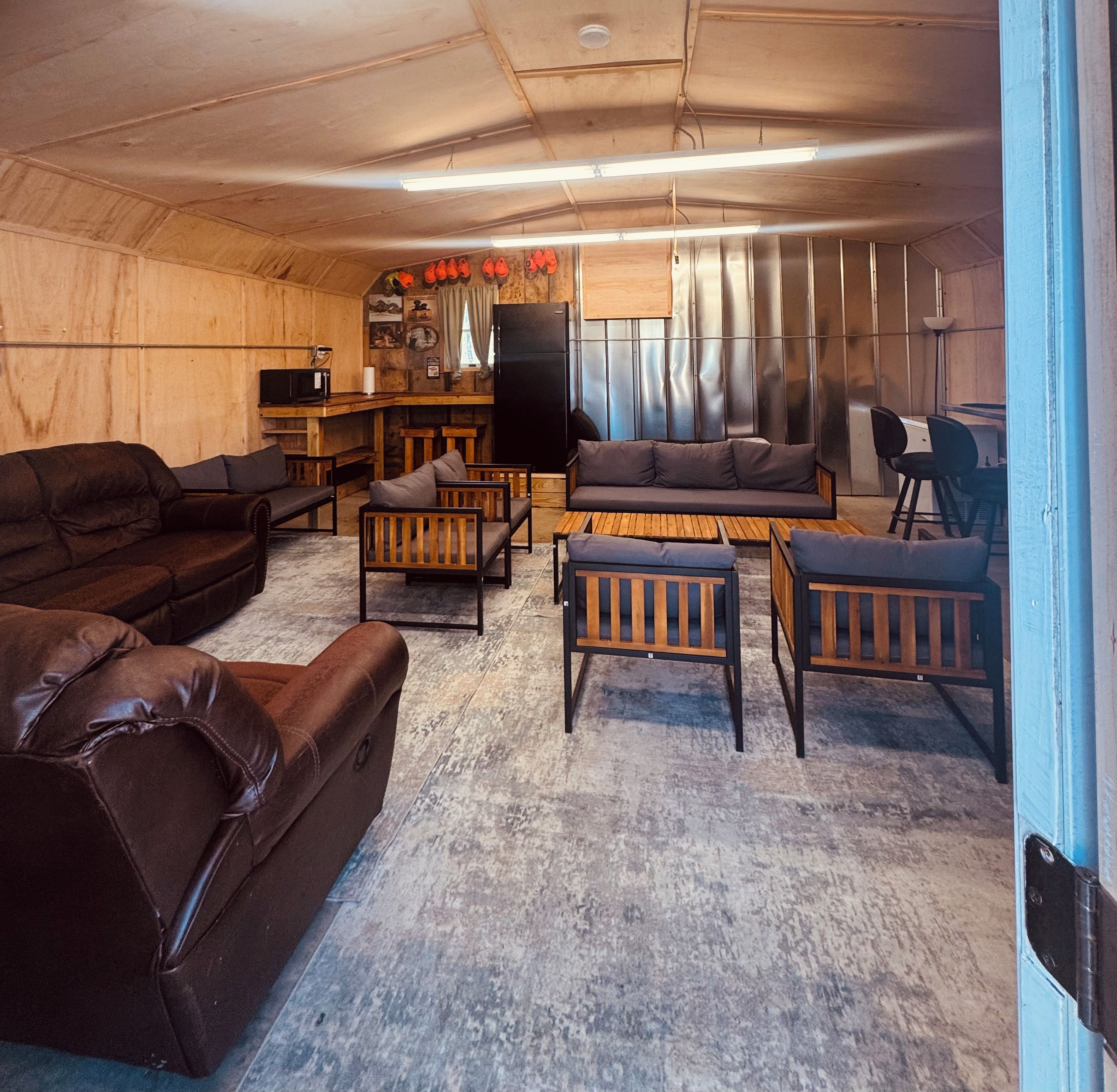 A cozy living room with a sofa, chairs, a coffee table, and a bar area with a refrigerator and counter.