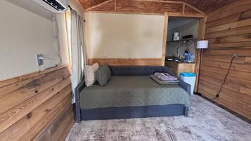 Ein kleines Schlafzimmer mit einem Bett, einem Nachttisch und einem kleinen Beistelltisch.