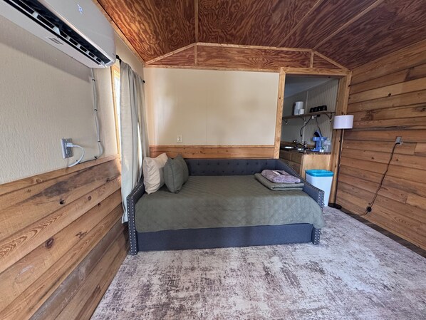 A compact bedroom with a bed, a small bedside table, and a nightstand.