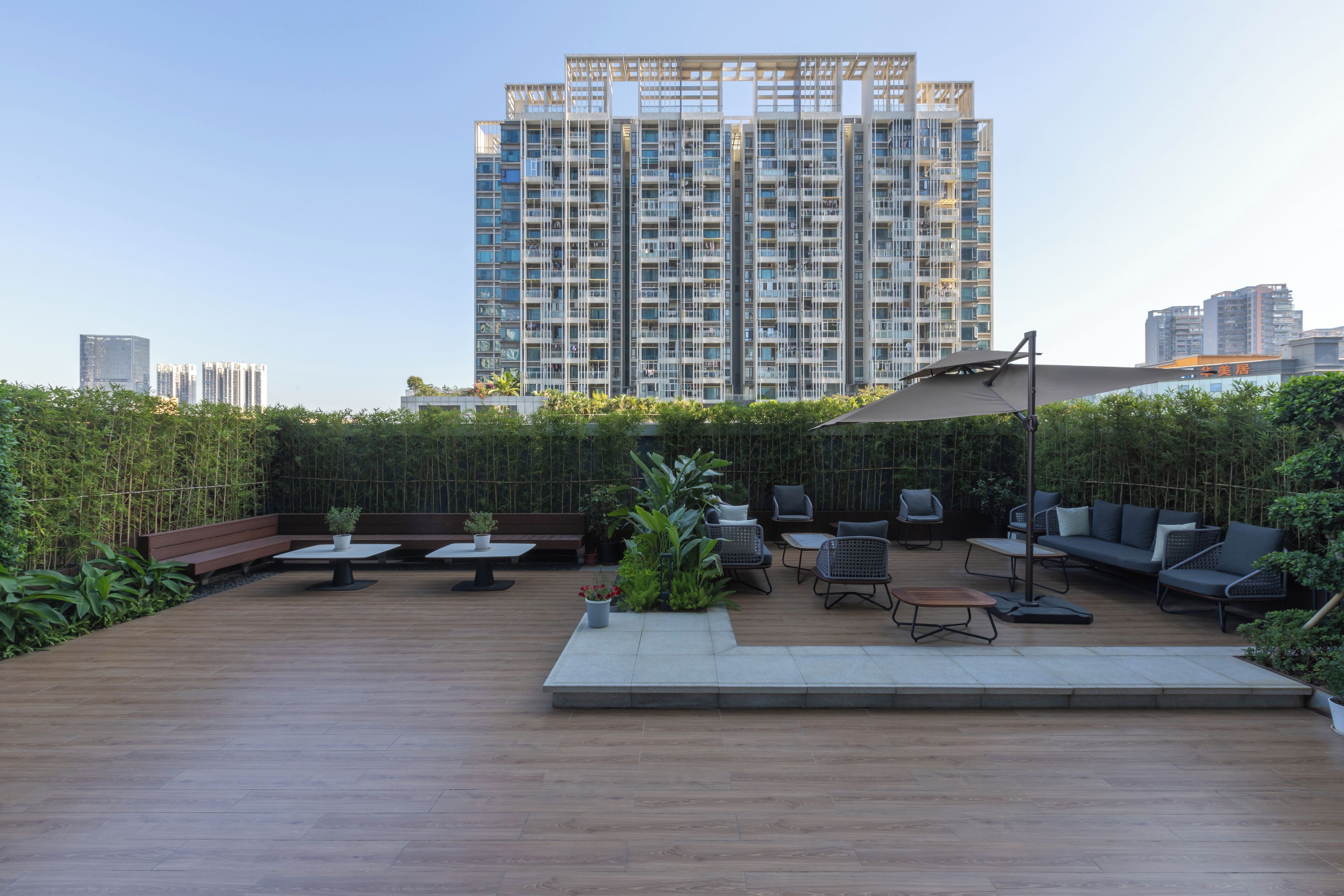 A rooftop patio with outdoor seating, a pergola, and a view of a high-rise building.