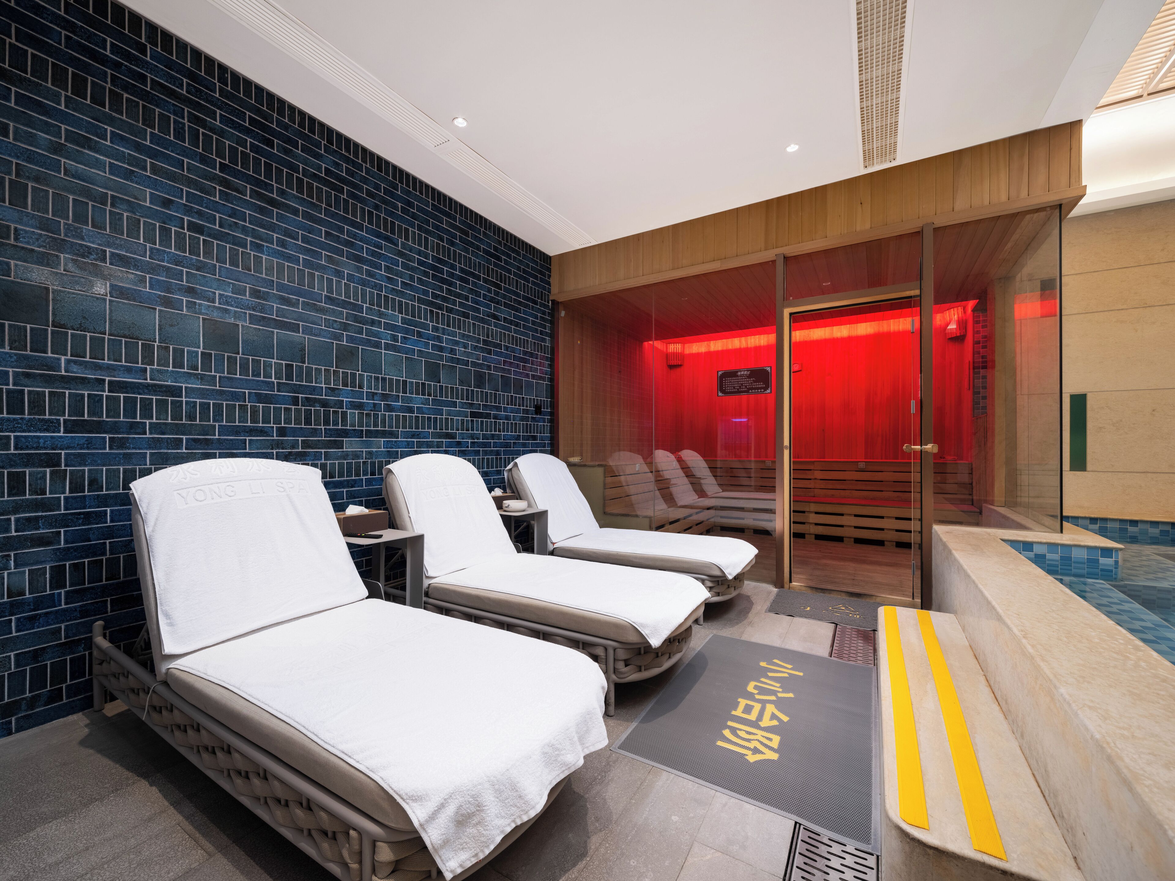 A spa area with massage chairs, a reception desk, and a red-lit sauna room.