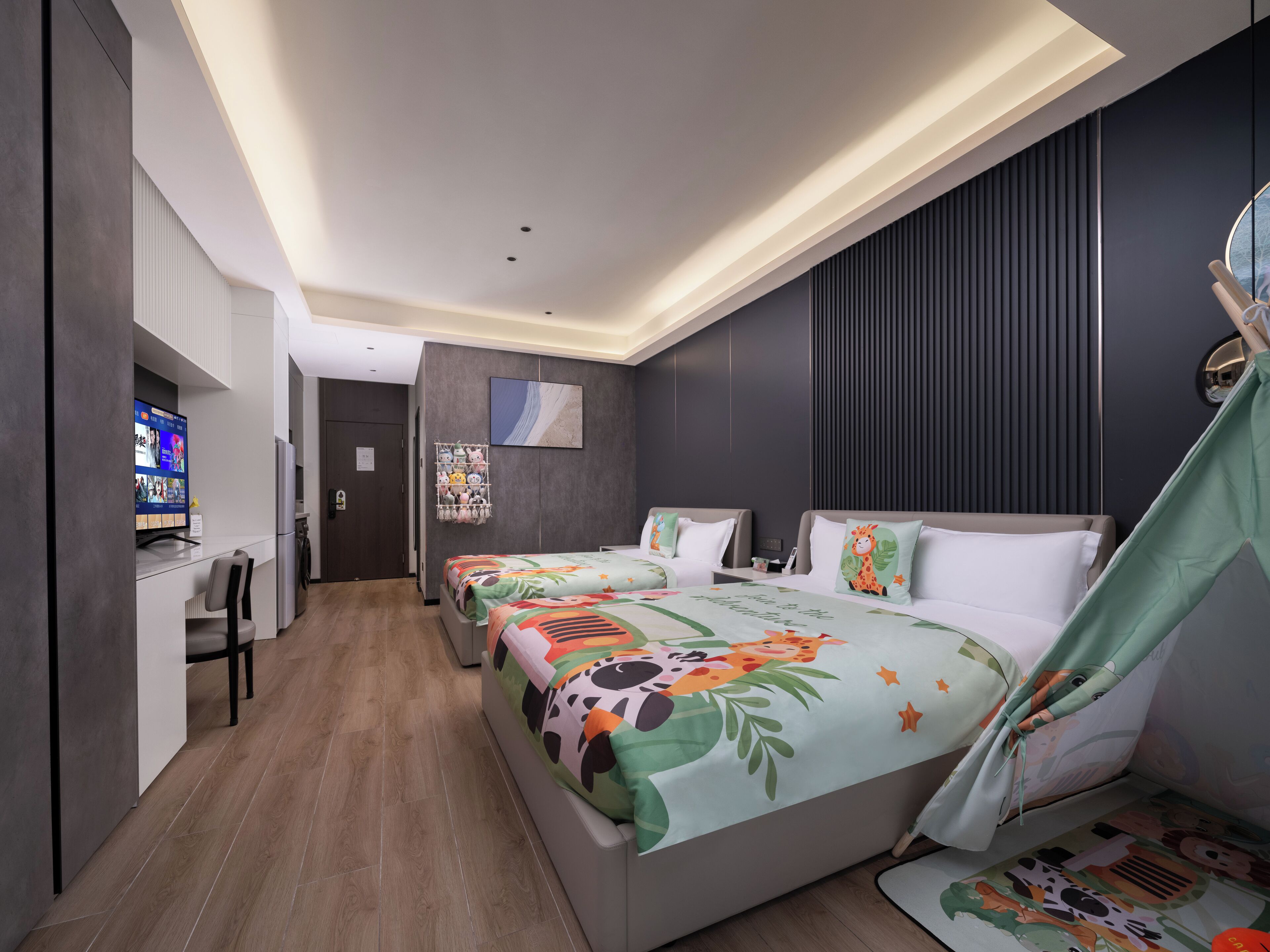A modern hotel room with two beds, a desk, and a TV.