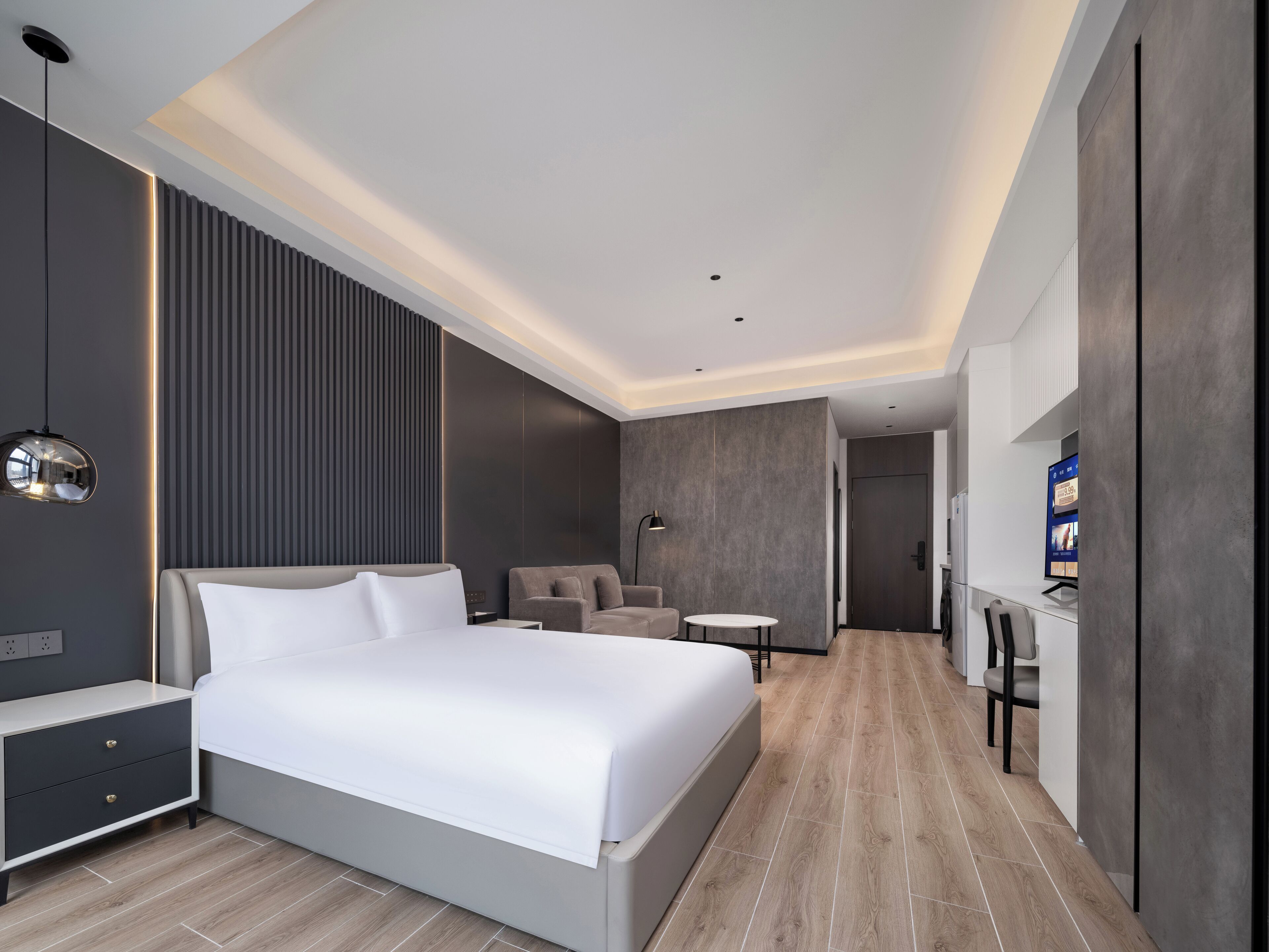 A modern hotel room with a large bed, a desk, a chair, and a TV.