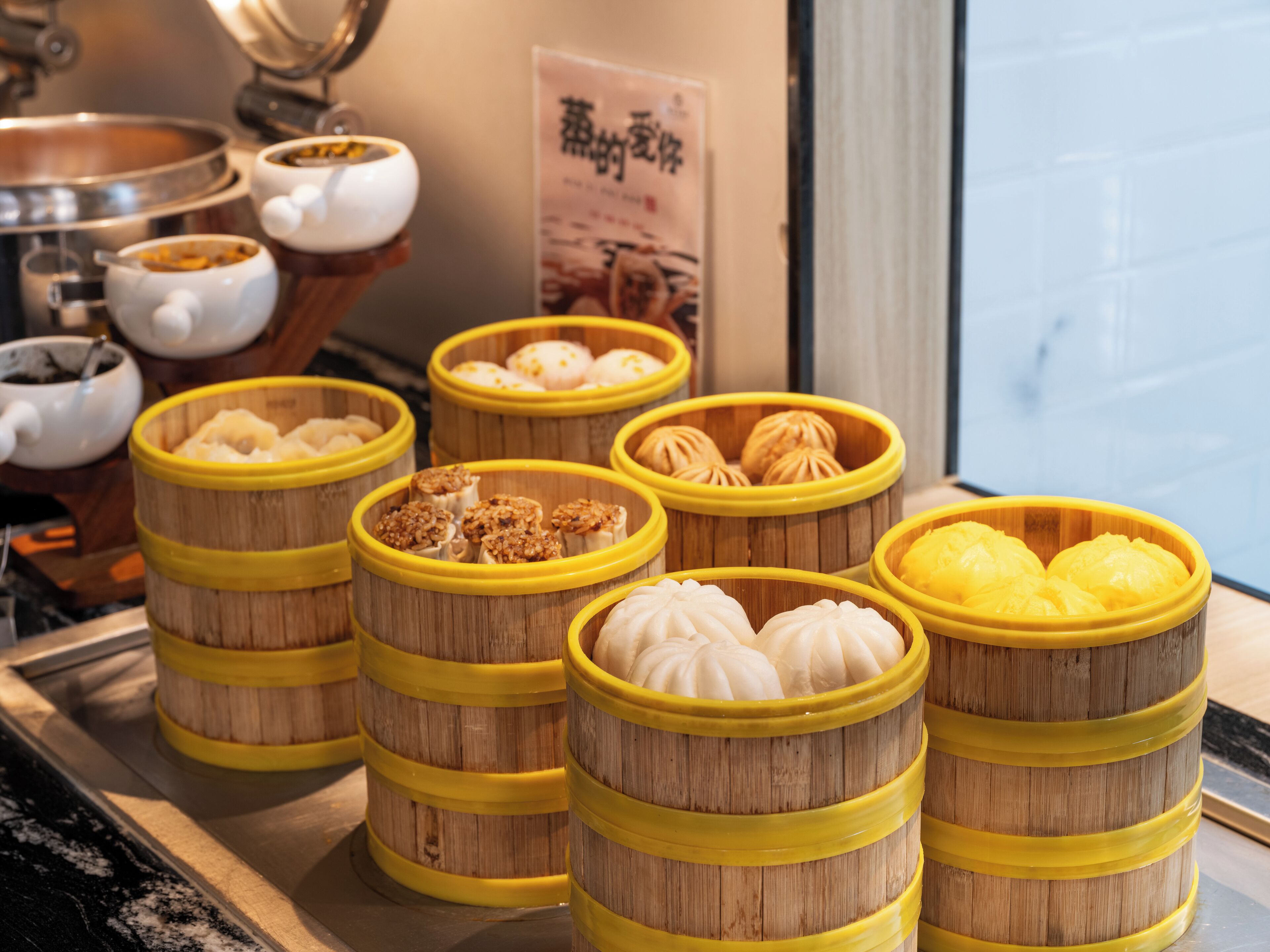 A display of various steamed buns in bamboo steamers, arranged on a counter.