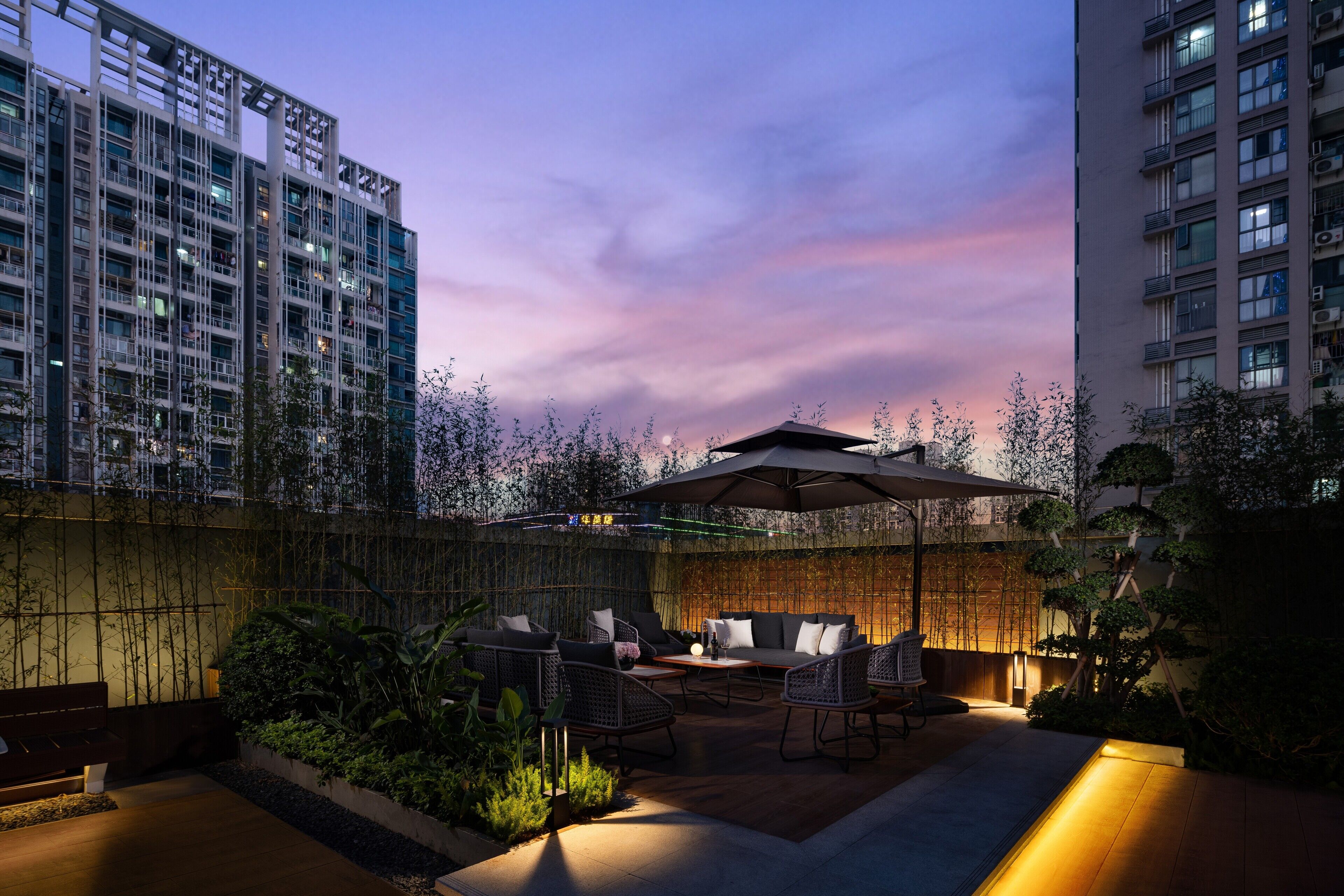 A rooftop patio with outdoor seating, a pergola, and a view of high-rise buildings.