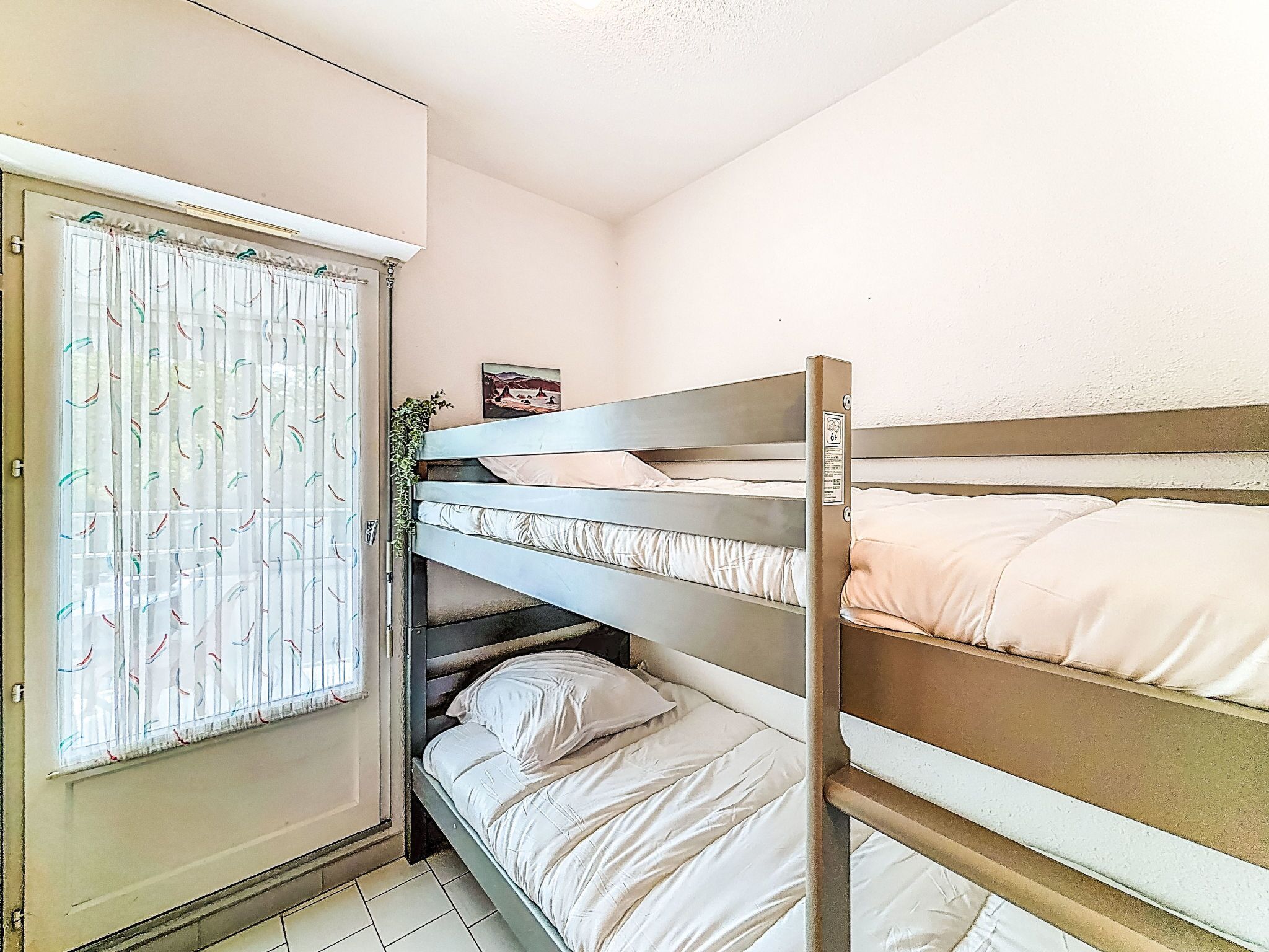 A bunk bed room with a wardrobe and a window with curtains.
