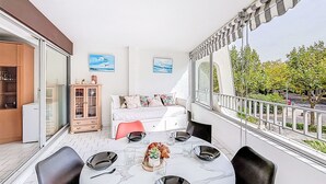Un balcon avec une table à manger, des chaises et un canapé. Deux tableaux encadrés sont accrochés au mur.