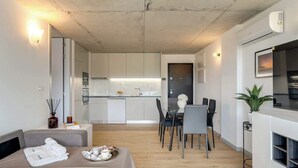 Un apartamento moderno con comedor, kitchenette y sala de estar con sofá y una bandeja de objetos.