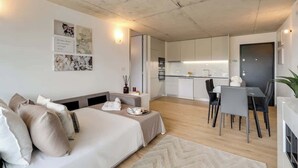 Una sala de estar moderna y minimalista con un sofá, un comedor con mesa y sillas, y una cocina al fondo.