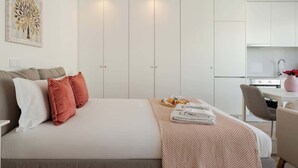 Una habitación de hotel moderna con una cama grande, un comedor y una kitchenette.