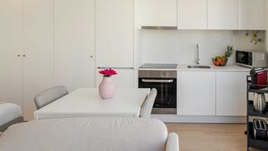 Una cocina moderna con armarios blancos, horno empotrado y microondas.