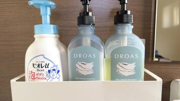 Trois flacons du traitement et du shampooing DRAAS, à la texture soyeuse, sont posés sur une étagère blanche.