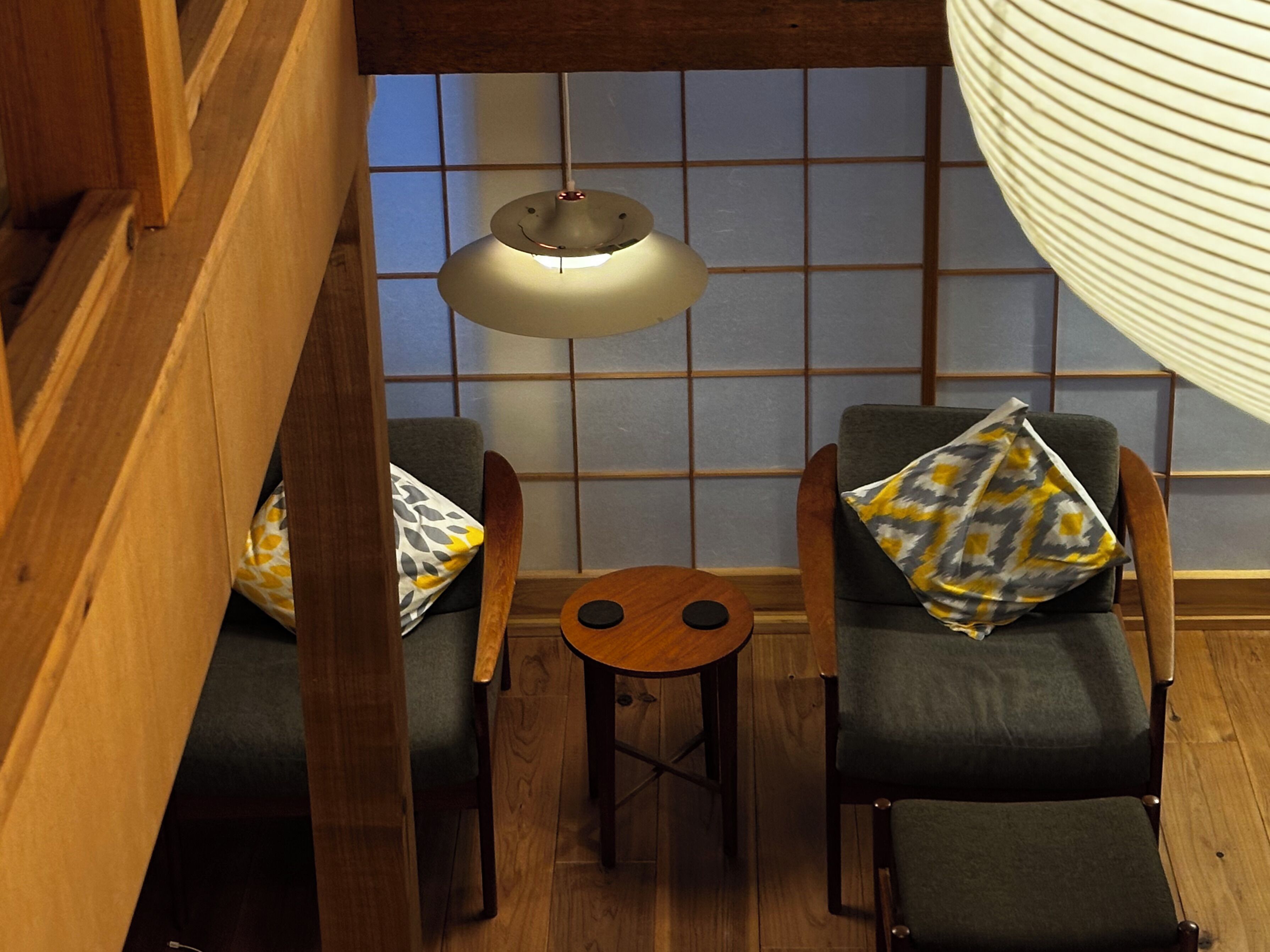 A small, cozy room with two chairs, a small table, and a hanging light fixture.