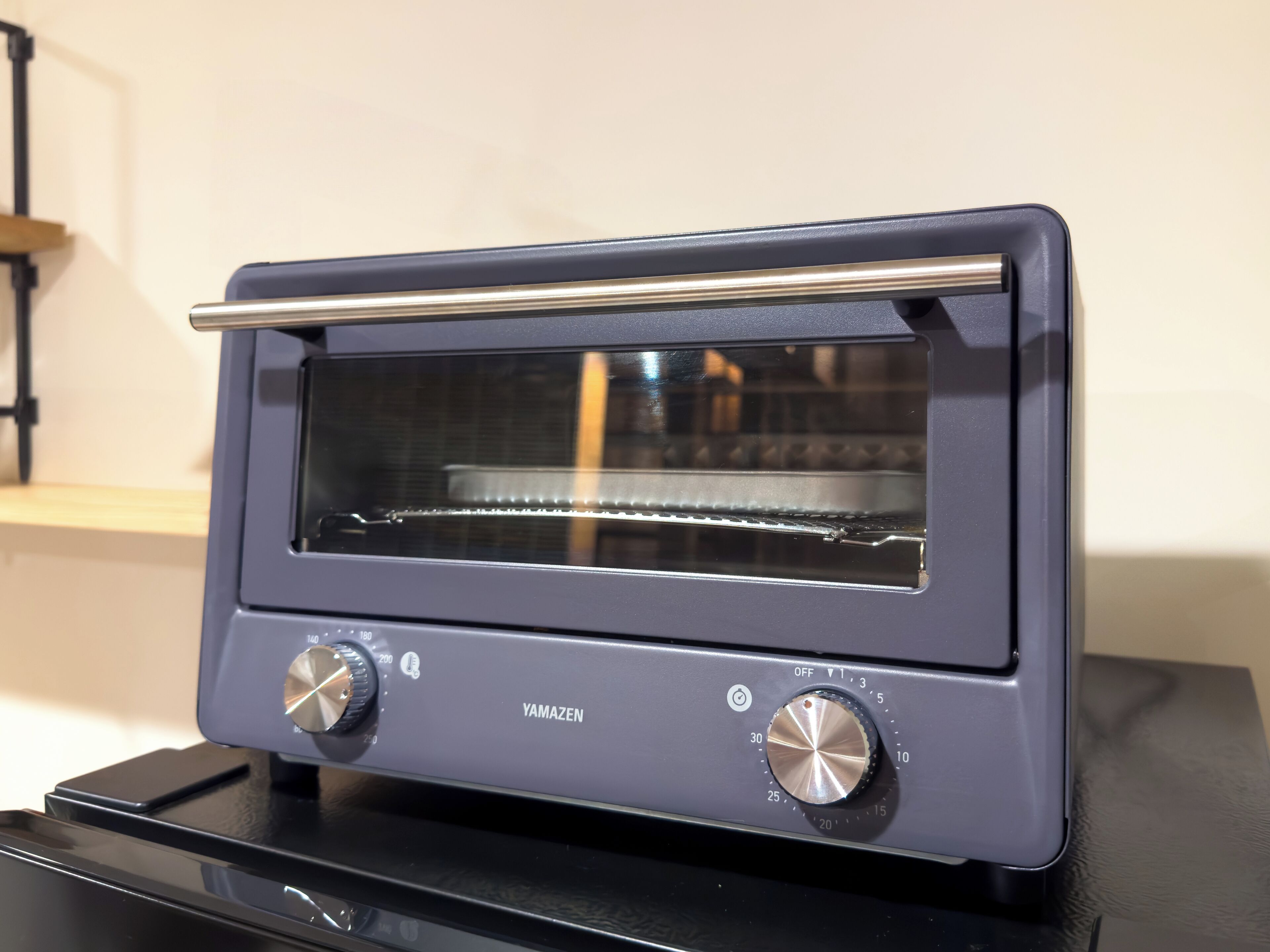 A YAMAZEN toaster oven with two control knobs and a glass door, placed on a black countertop.
