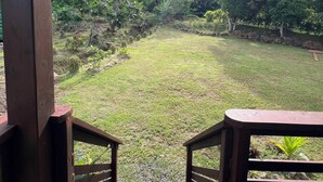 A wooden staircase leading to a grassy area with a view of dense foliage and trees. - Hava'i Lodge (Raiatea)
