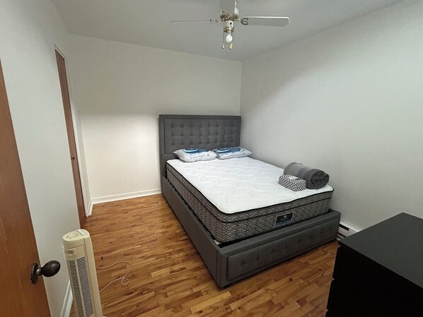 Une chambre à coucher avec un lit, un ventilateur de plafond et un radiateur.
