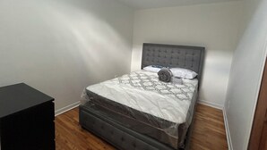 A bedroom with a bed, a small black dresser, and a skylight.