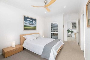 Ein Schlafzimmer mit einem Bett, einem Nachttisch, einem Deckenventilator und einem Bild an der Wand.
