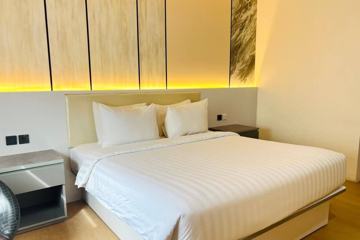 Ett modernt hotellrum med en stor säng, sängbord och en väggmonterad lampa.