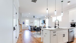 Una cocina moderna con armarios blancos, una isla central e iluminación colgante.