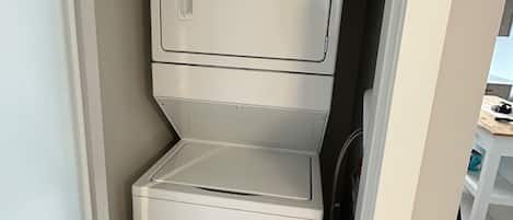 A compact, white Whirlpool washer and dryer unit in a small laundry room with a tiled floor.