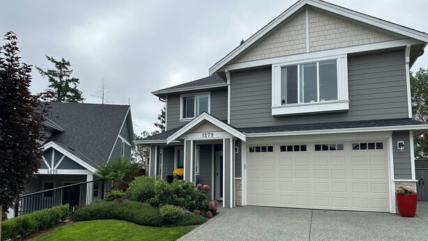 A two-story house with a garage, a well-maintained lawn, and a driveway. - Modern One-Bedroom Retreat in Bear Mountain (Langford)