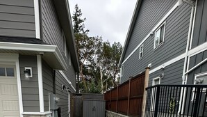 A residential area with a paved driveway, a red planter, and a stone wall. - Modern One-Bedroom Retreat in Bear Mountain (Langford)