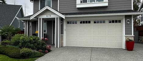 Une maison à deux étages avec un garage, une allée et une pelouse bien entretenue.
