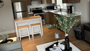 A modern kitchen with wooden cabinets, stainless steel appliances, and a central island. - Modern One-Bedroom Retreat in Bear Mountain (Langford)