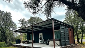 A covered outdoor area with a wooden deck, a barbecue grill, and a seating arrangement.