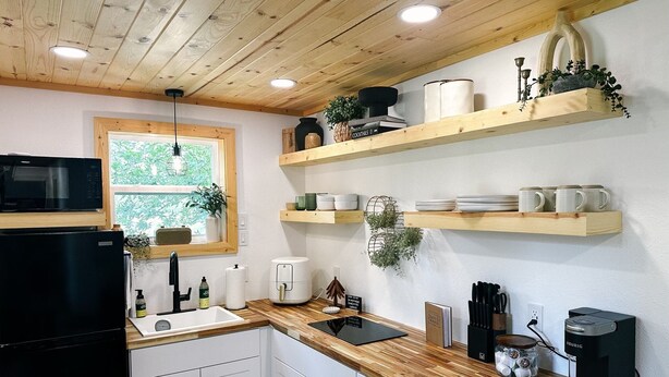 A modern kitchen with wooden cabinets, a microwave, a sink, and a coffee maker.