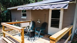 Une terrasse en bois avec un banc, deux chaises et une table agrémentée d’une plante.