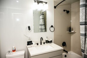 Ein modernes Badezimmer mit einem weißen Waschbecken, einem schwarzen Wasserhahn und einem Handtuchhalter.